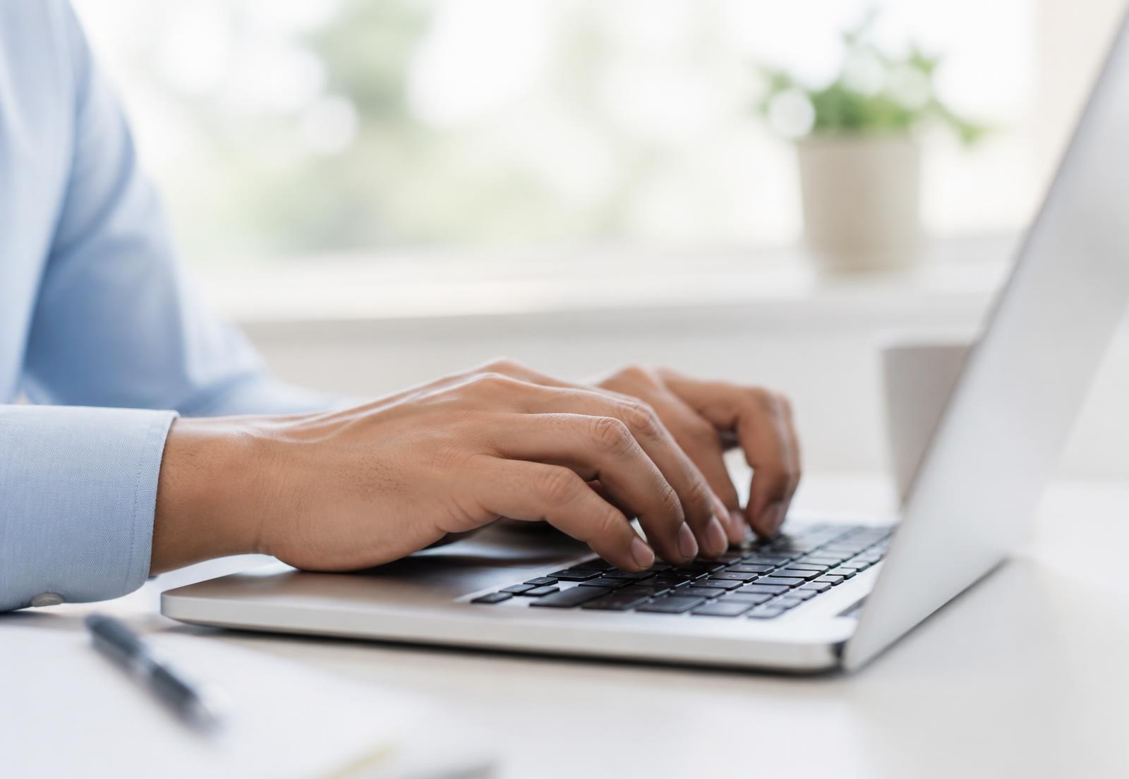 A laptop showing search analytics on a bright home-office desk, with a notebook, pen, and coffee mug